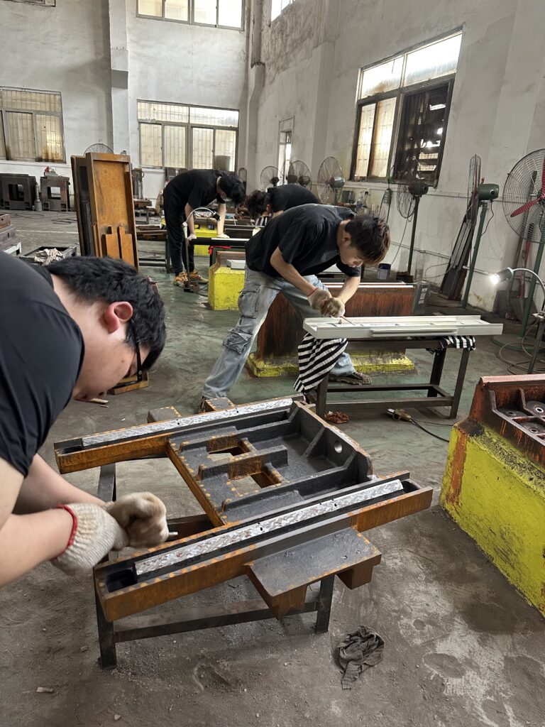 YUTON workers performing precision hand scraping on grinder table and saddle guideways