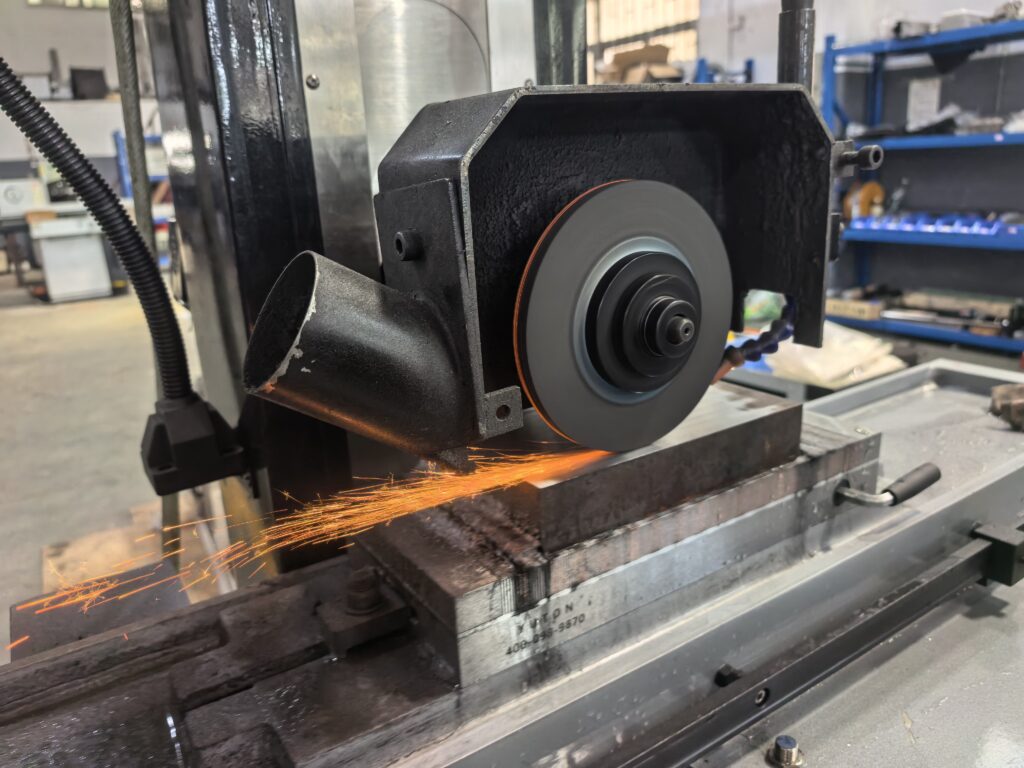 YUTON automatic surface grinder in operation showing grinding sparks during precision surface grinding process