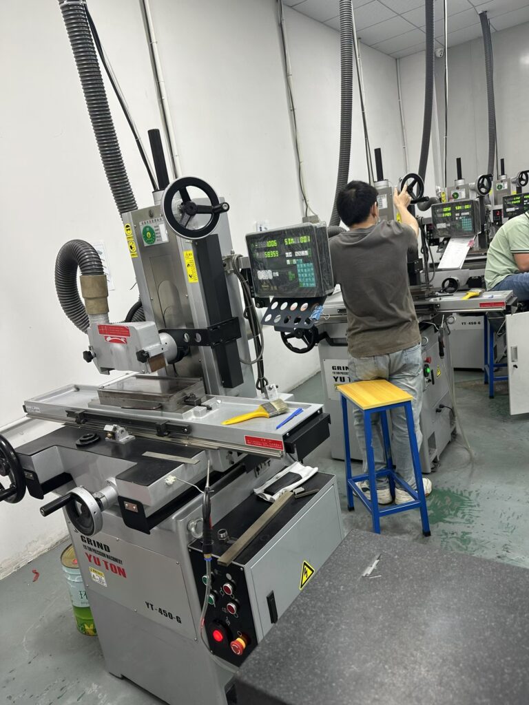 Operator using hand feed controls on a manual surface grinder